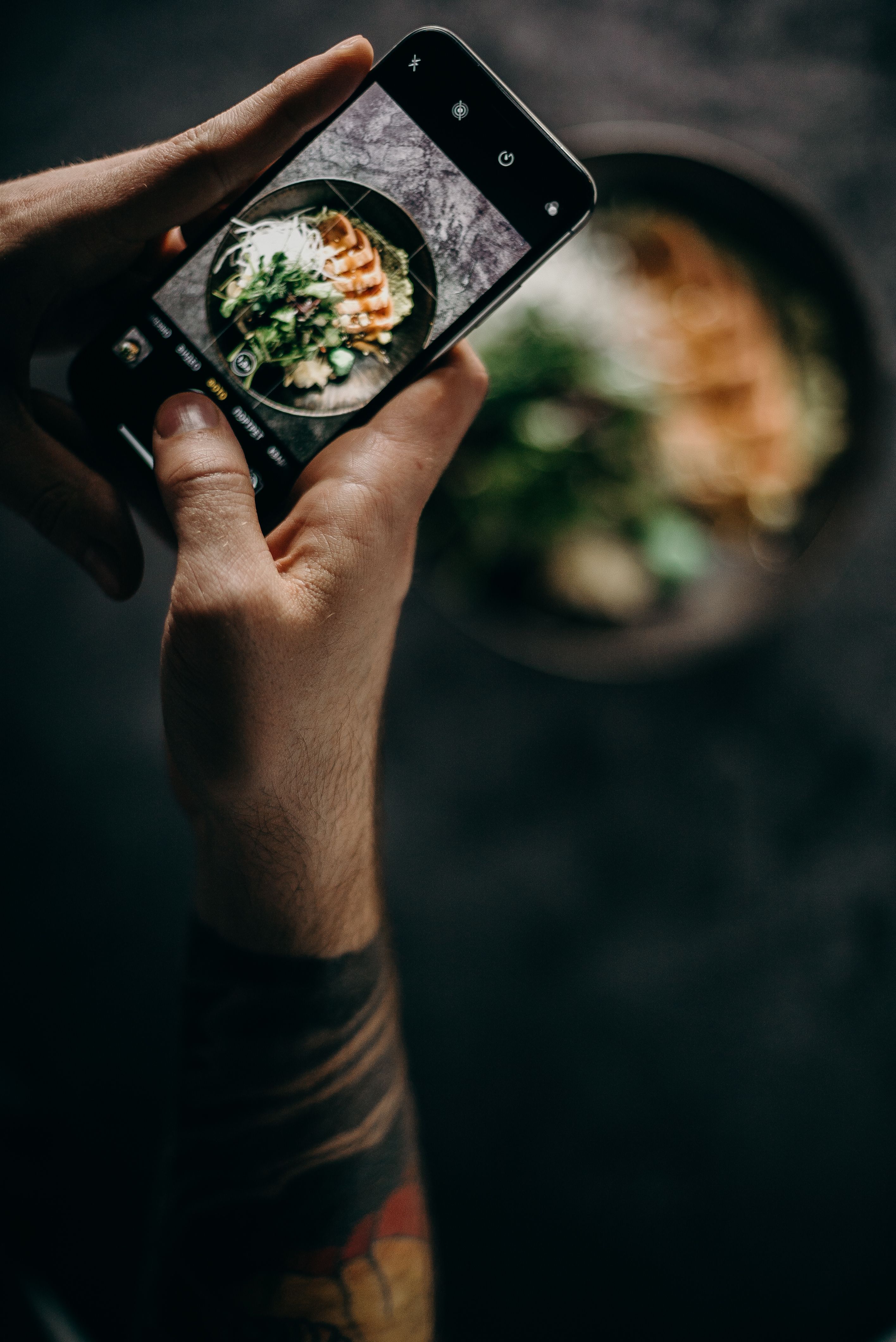 Chef framing a finished bowl on an iPhone for a social post